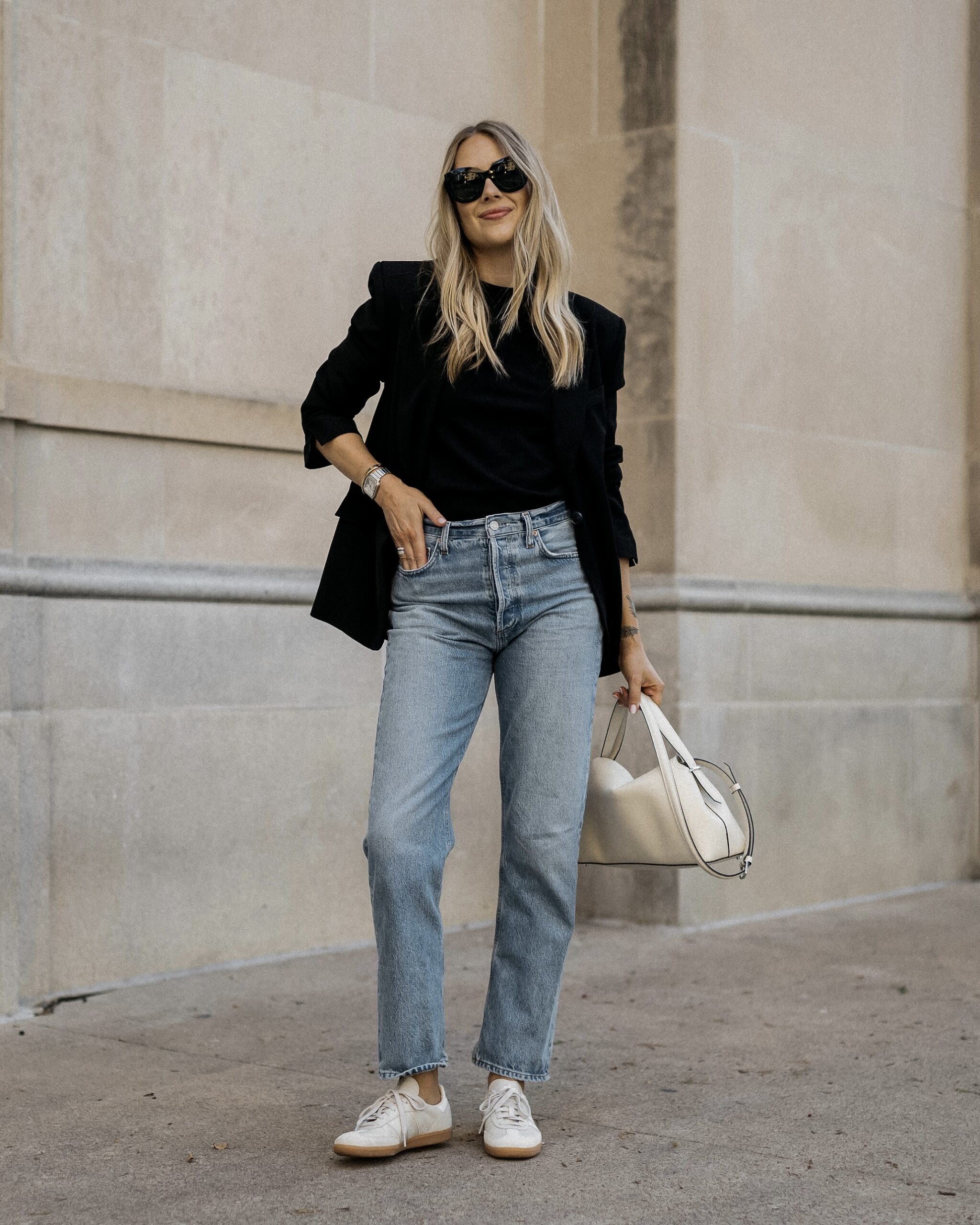 Black blouse, blue jeans and a small white handbag