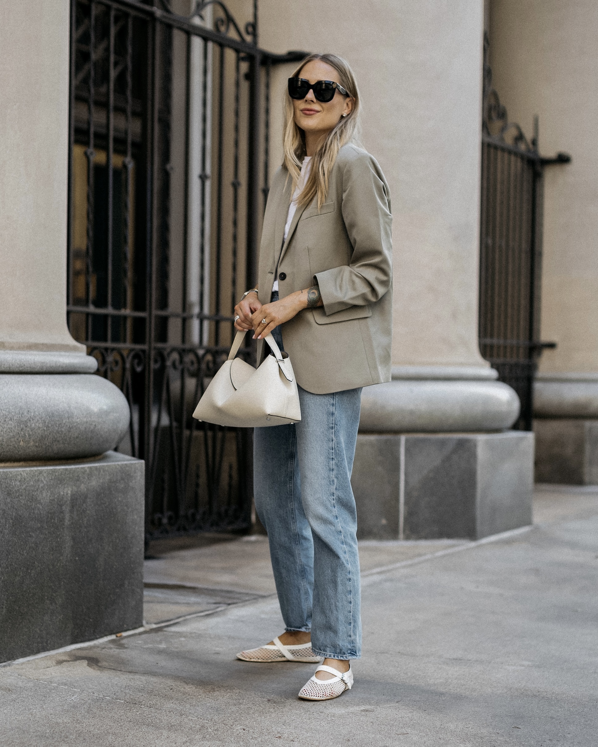 Grey blazer and white shirt with blue jeans, white flats and a light handbag