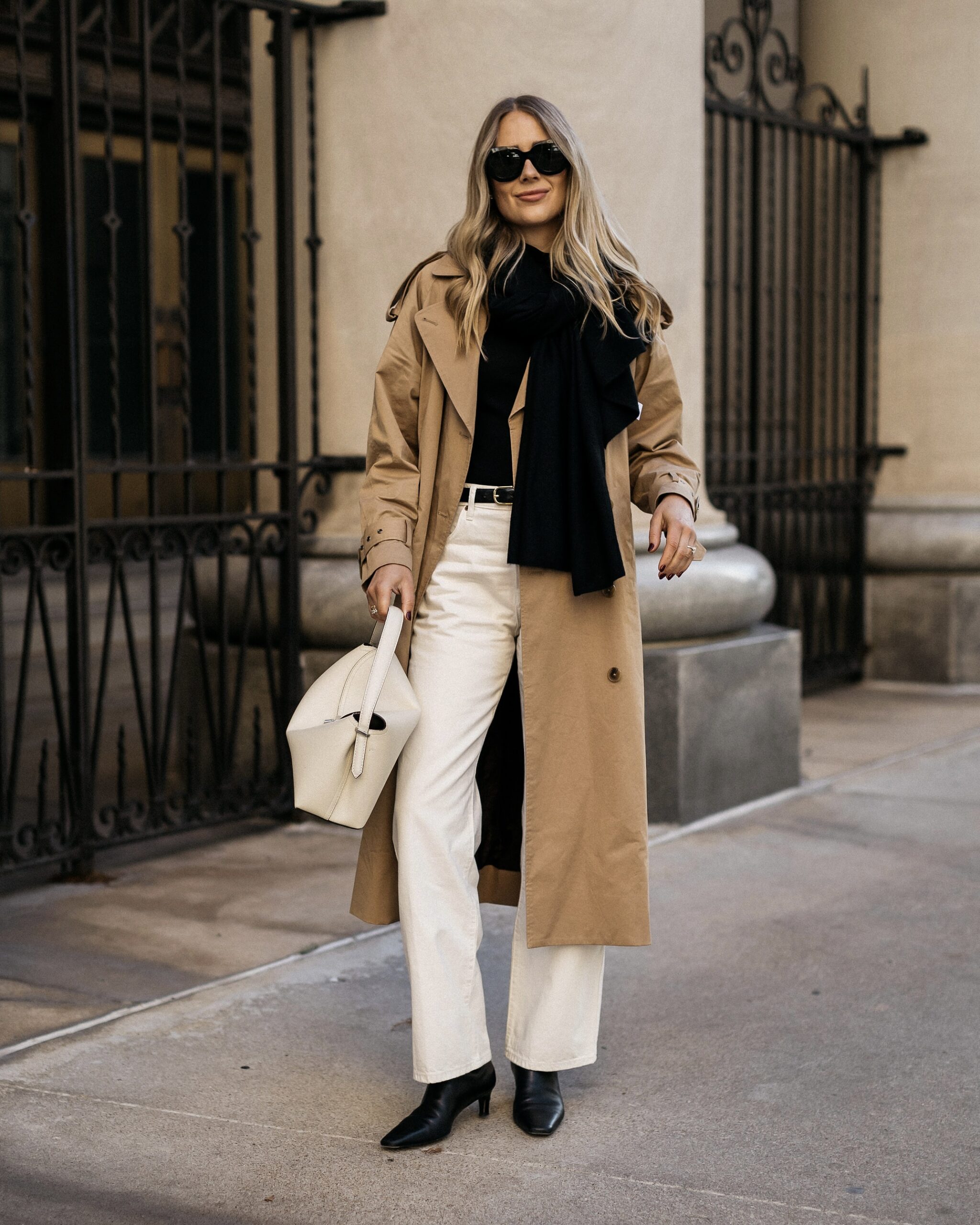 Long camel trench with a black scarf, white jeans and black ankle boots