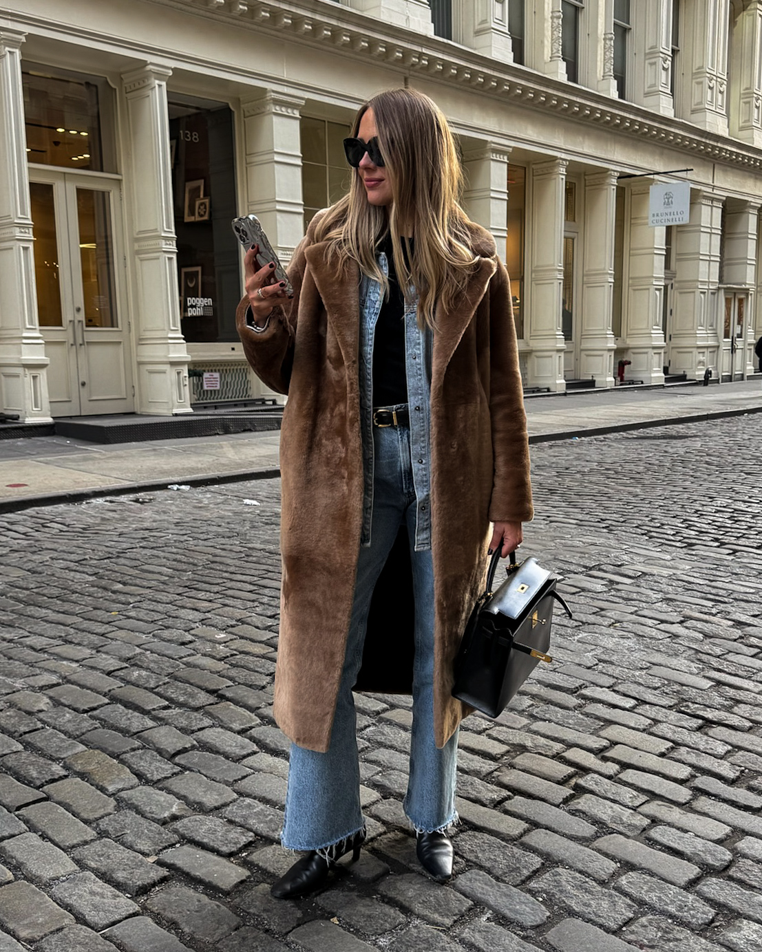 Long brown coat over a denim shirt and blue jeans with black ankle boots