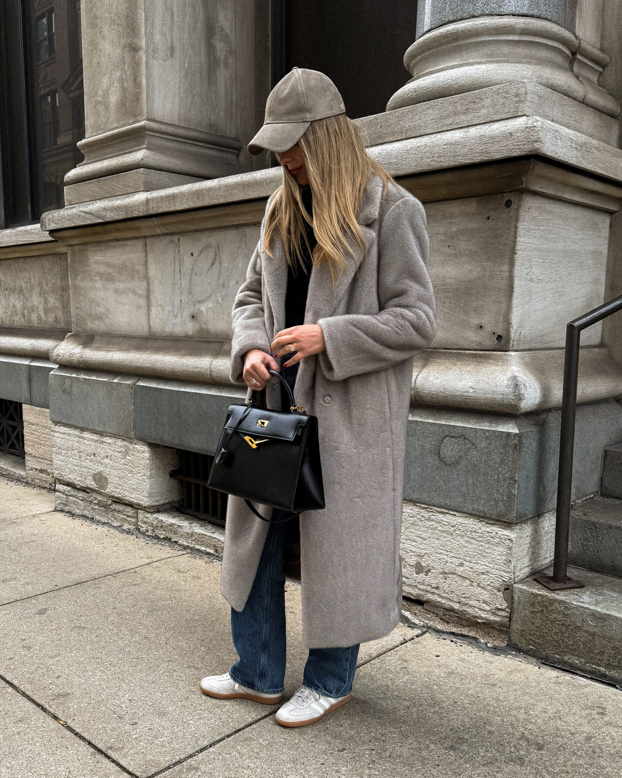 Grey coat and knitted hat with blue jeans, white sneakers and a black handbag